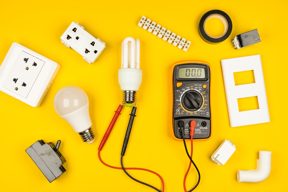electrical tools, bulbs, and sockets on yellow table top.
